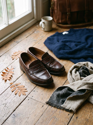 Dark leather penny loafers on an oak floorboard