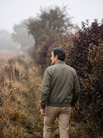 Man walking a hedgerow path in October mist